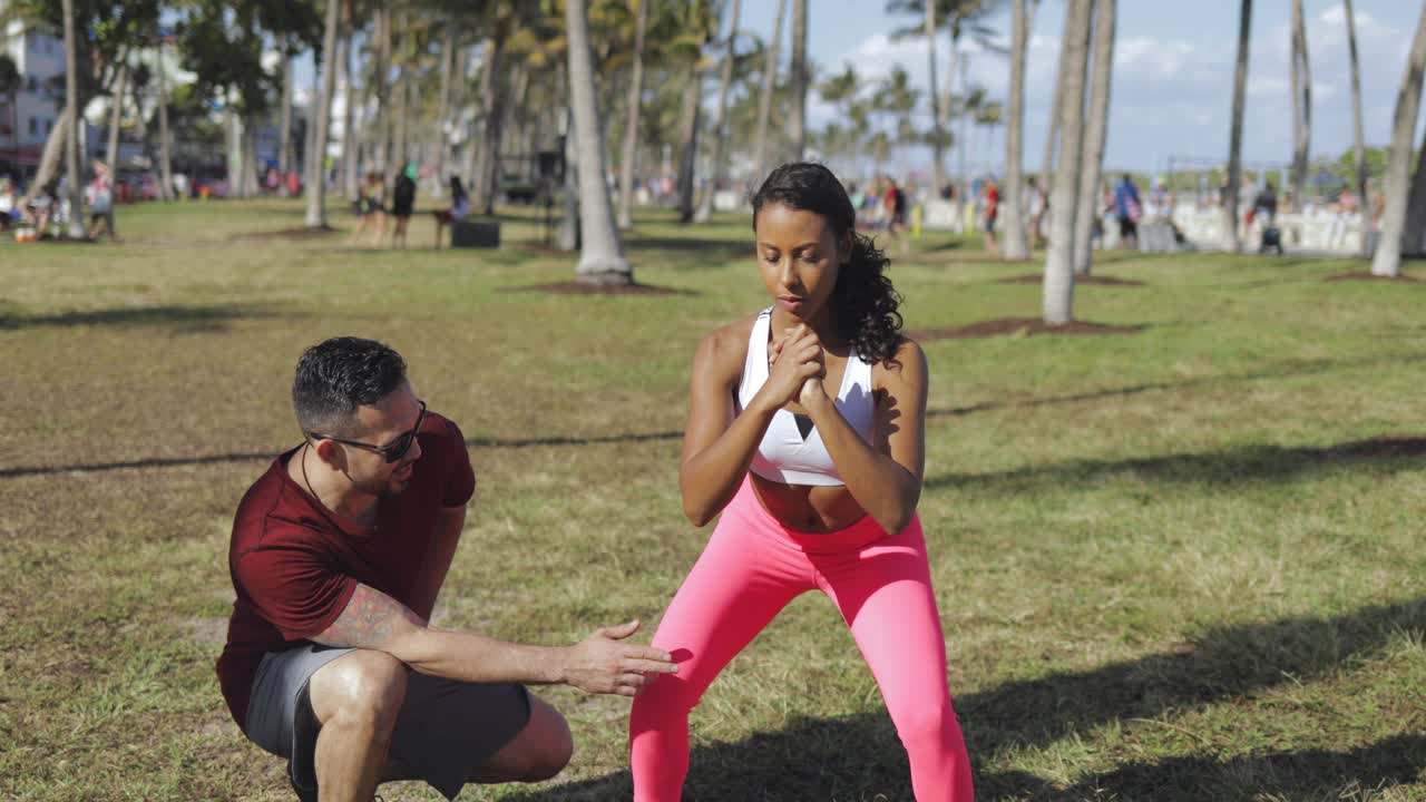 hombre ayudando a una chica con la técnica de sentadillas