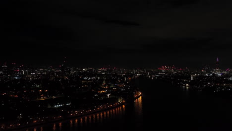 aerial view rising from the isle of dogs, at thames river and london skyline, night