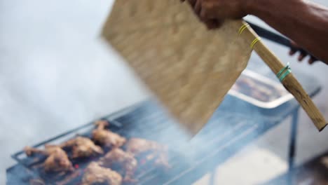 Toma-En-Cámara-Lenta-De-Un-Vendedor-Ambulante-Asiático-Cocinando-Ayam-Bakar-En-Una-Parrilla-Humeante