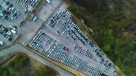 drone rotates and rises above parked cars in port lot ready for transport