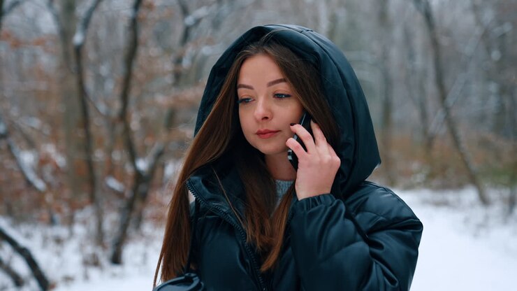 Lady in black blazer walks with paper cup in the park. Woman answers the phone and continues to walk.