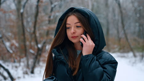 lady in black blazer walks with paper cup in the park. woman answers the phone and continues to walk.