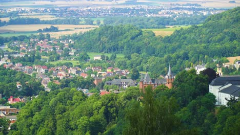 top-bird-view-of-a-cities-and-villages-around-Czech-Republic-surrounded-by-nature-forests-and-fields-mainly-red-coloured-roofs-sunny-day-a-brown-castle-royal-palace-pointed-towers-for-high-class