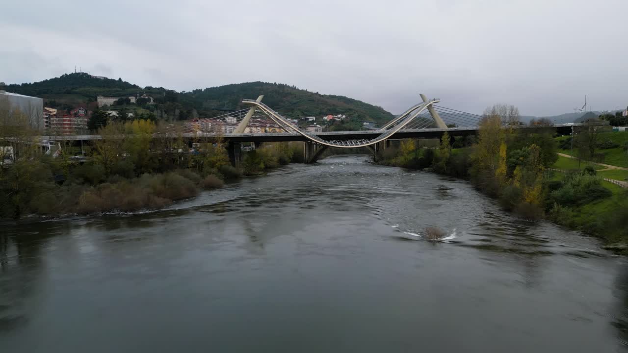 Slow aerial dolly above river to Millennium Bridge Mi&ntilde;o River in Ourense, Galicia, Spain as seagull soars