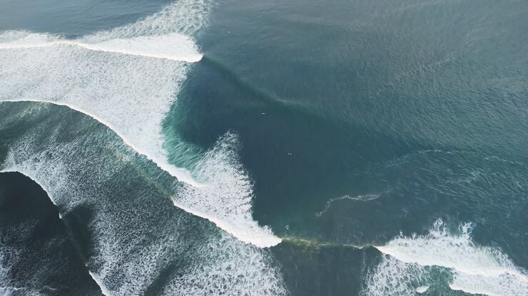Balian surfers beach with blue green waves swelling along the shoreline with tiny surfers dwarfed by the swell