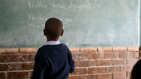 Schoolboy-writing-on-chalkboard-in-classroom-4k