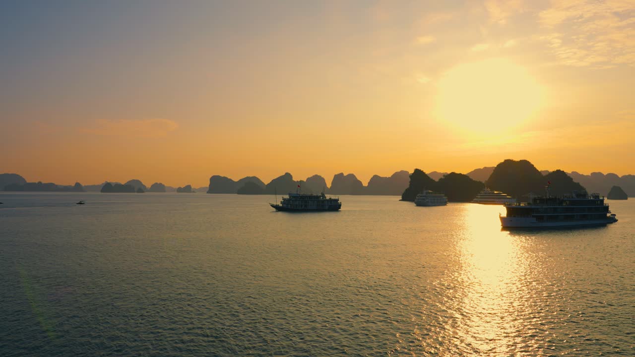 Aerial Landscape of many cruise ships anchored at Halong Bay backlit with rising bright sun, Vietnam