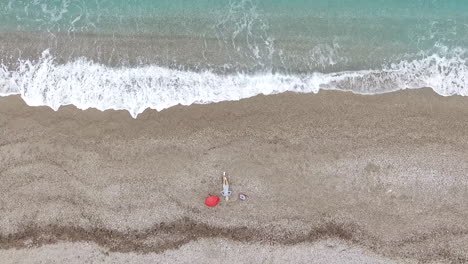 luftansicht einer person, die sich an einem strand mit wellen entspannt