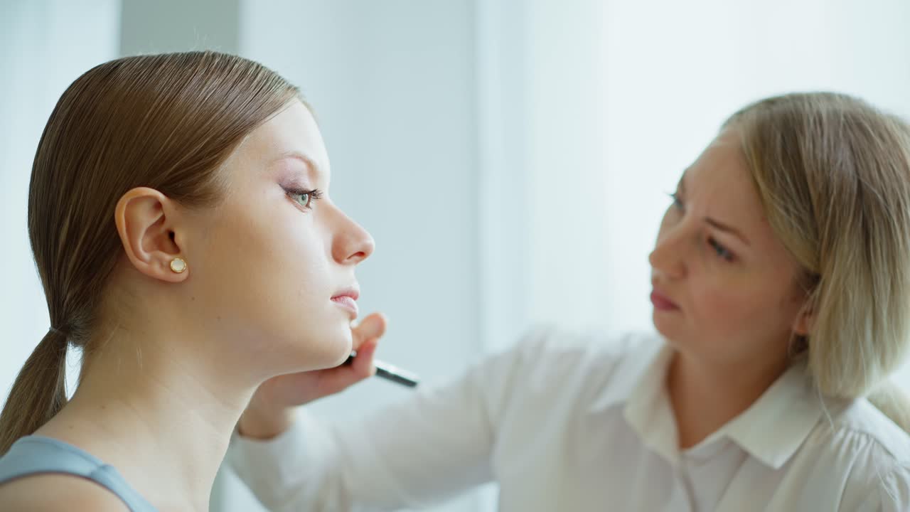 artista de maquillaje aplicando maquillaje a una mujer joven