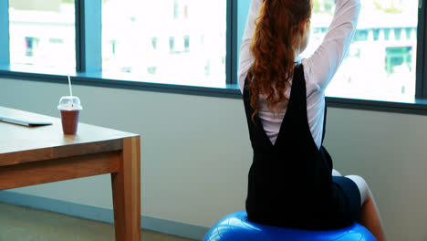 female executive performing yoga at her desk