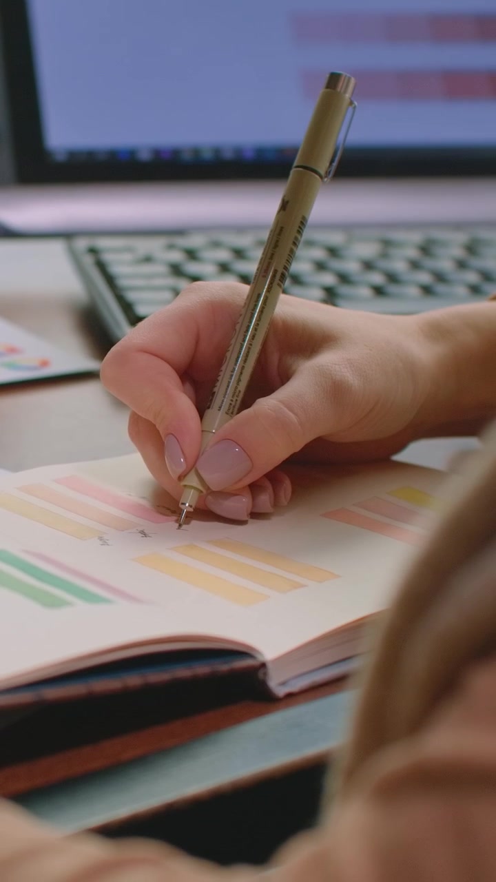 Close-up of a Person Writing in a Planner at a Desk