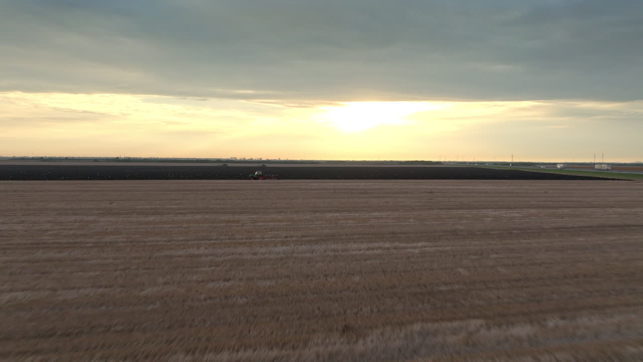 Traktor pløjer mark ved solnedgang