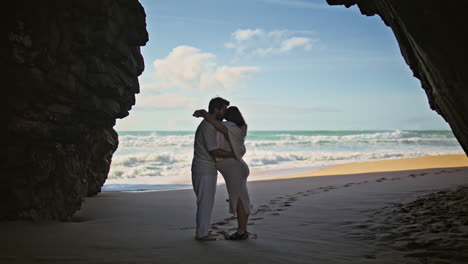 tender couple enjoy pregnancy hugging on sunny ocean shore. spouses on beach