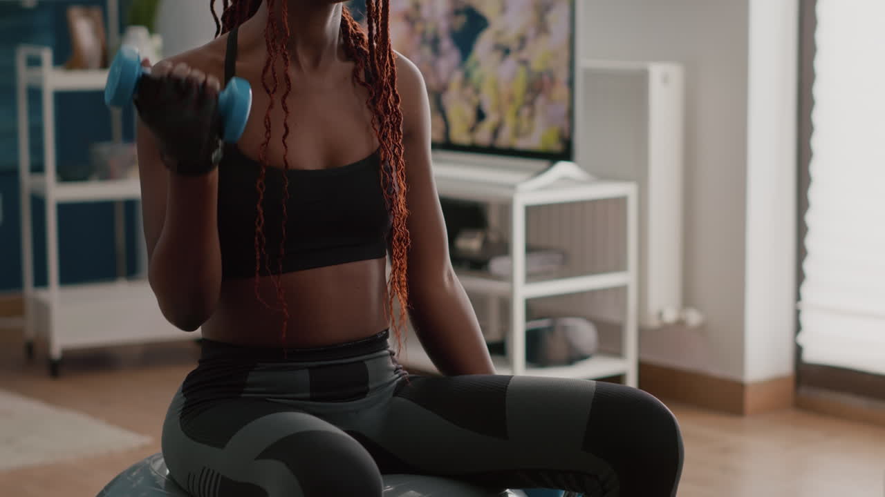 Slim woman with black skin doing exercises with fitness dumbbells