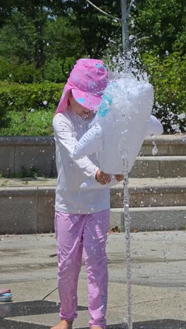 little girl splashing water at a park fountain in seoul on a hot summer day, dressed in sun-protective swimwear and hat