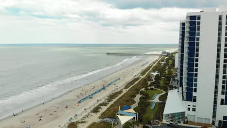 aerial push-in shot toward myrtle beach coastline past large building during midday