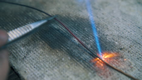 heating of wire with gas burner on fireproof sheet closeup