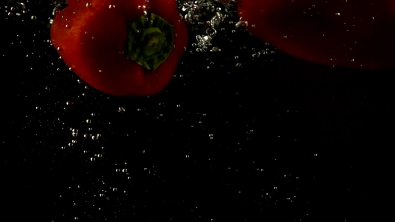 Padající sladká paprika. Zpomalený záběr. Černé pozadí.