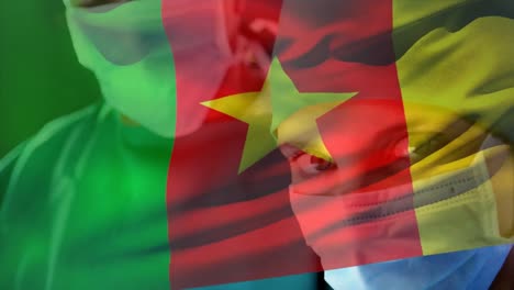 Digital-composition-of-cameroon-flag-waving-against-female-surgeon-wearing-face-mask-at-hospital