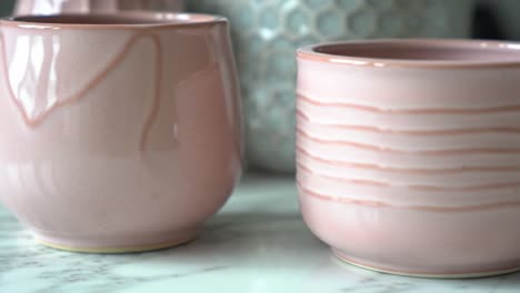 elegant pink pottery: a close-up view of beautifully crafted pink ceramic containers on a marble surface, showcasing their unique designs and textures