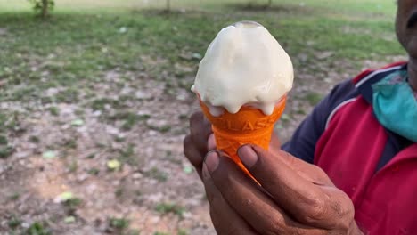 un personal masculino en uniforme prepara cuidadosamente el hielo cubierto de nieve del carrito de helado de vainilla al aire libre