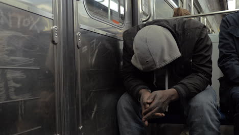 hombre sin hogar con ropa desaliñada viajando en el tren del metro