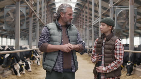 male dairy farm owner giving tasks to boy