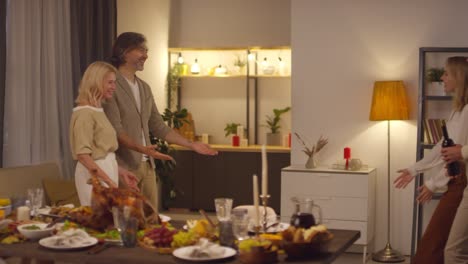 wife and husband welcome their son and daughter in law into in living room to celebrate thanksgiving