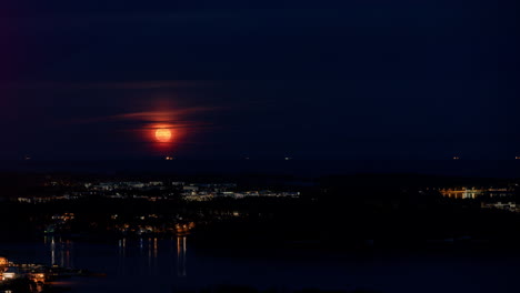 Time-lapse-of-the-Moon-rising-above-illuminated-Laajasalo,-night-in-Helsinki