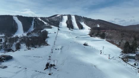 ascending drone shot flying high above ski area, moving chair lifts and skiers and snowboarders below