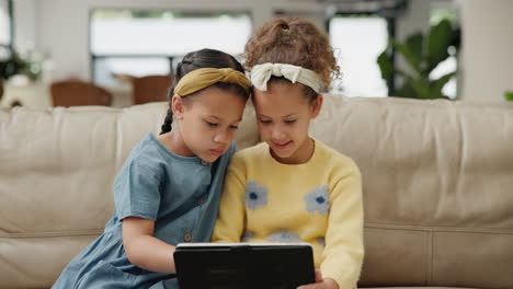 dos hermanas usando una tableta en un sofá