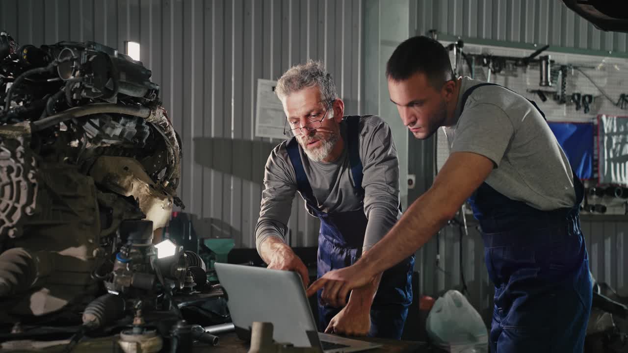 Automotive Technicians Working on a Car Engine with Laptop
