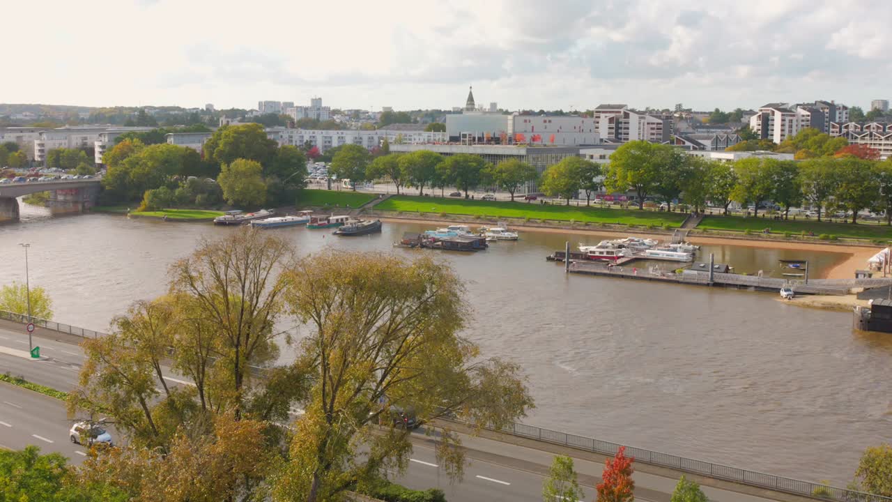 Panoramic riverside view with boats, trees and cityscape in Angers, France