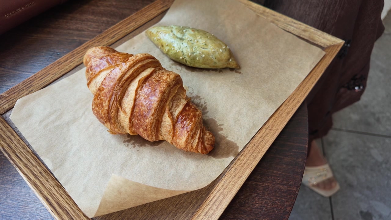 Mano che prende una brioche fresca da un vassoio di legno