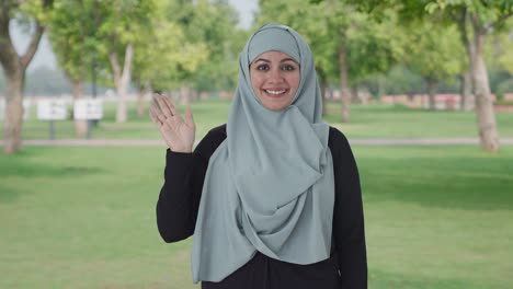 happy muslim woman saying hi in park