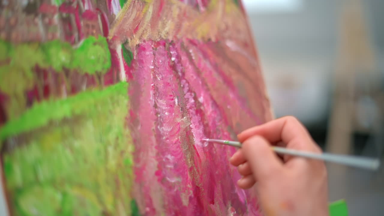 A woman painting a picture using a brush in a studio. Slow motion