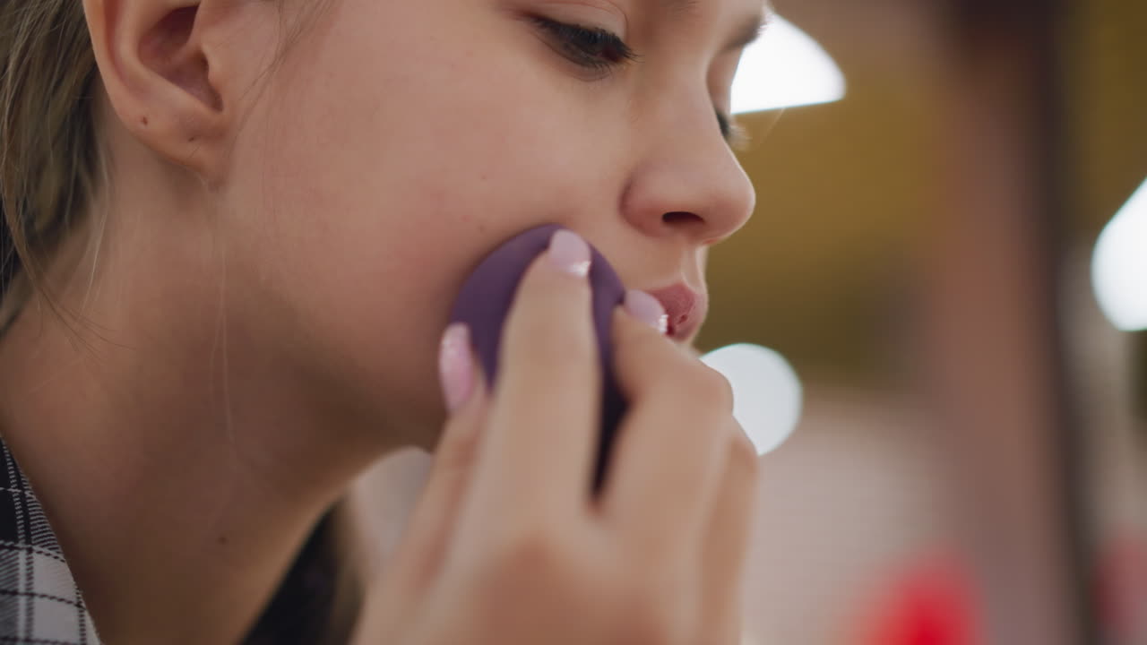 입 주변의 화장을 조정하는 여성의 클로즈업, 미용 스폰지를 사용하여 부드럽고 부드러운 피부, 균일한 재단 적용, 흐릿한 배경은 깊이를 더하고 아름다움을 향상시니다.