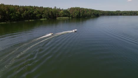 motorboat pulls cockpit tube on a lake, following drone shot