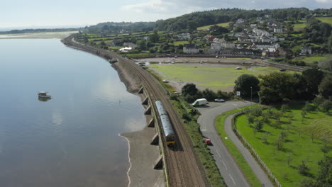 Toma-Aérea-De-Un-Dron-Siguiendo-Un-Tren-A-Lo-Largo-De-La-Costa-De-Devon-En-La-Desembocadura-Del-Río-Exe-Y-El-Tren-Desapareciendo-En-La-Distancia,-Ubicado-Cerca-De-La-Estación-Starcross