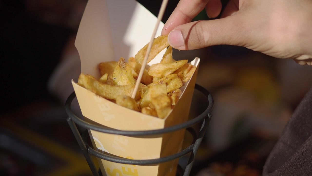 Persona che prende una patatina fritta da un cono di carta