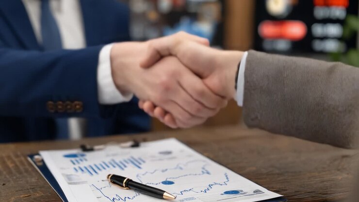 Una stretta di mano professionale che significa una negoziazione di successo e un accordo reciproco in un ambiente aziendale, con dati finanziari visualizzati su un documento.