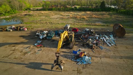 aerial view of junk yard with a big yellow grapple excavator in fayetteville, arkansas, usa