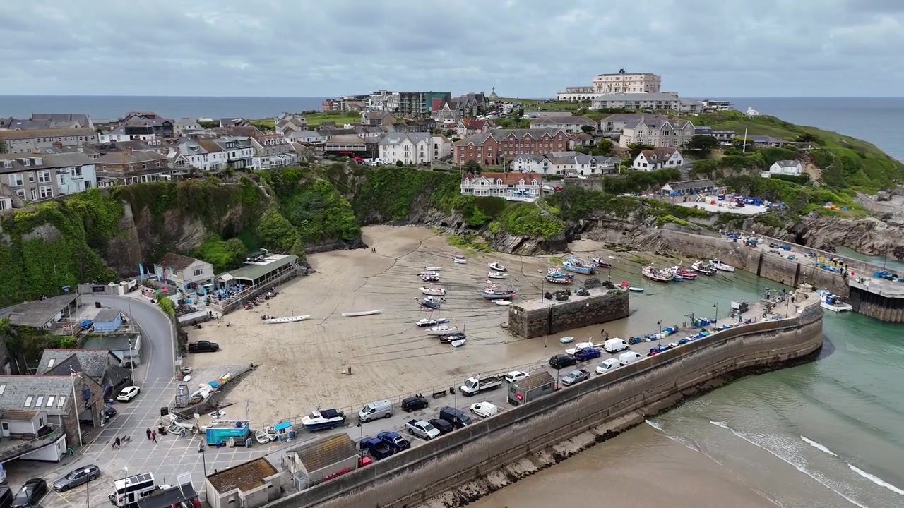 Atemberaubendes 4K-Drohnenmaterial, das den Hafen von Newquay bei Ebbe mit Fischerbooten, freigelegtem Sand und dem berühmten Atlantic Hotel, das die kornische Skyline dominiert, einfängt.