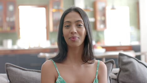 Young-biracial-woman-sits-comfortably-at-home