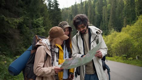 A-trio-of-tourists-get-lost-and-are-looking-at-a-map-to-figure-out-where-to-go-next.-People-in-hiking-clothes-sort-out-where-to-have-next-in-mountainous-terrain
