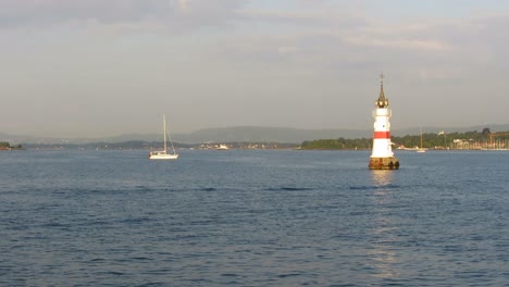 view from moving boat, passing lighthouse and sailboat