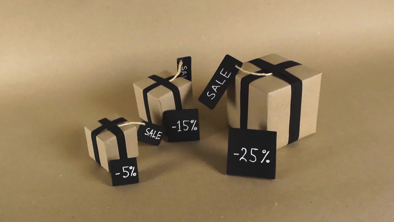 Roterend beeld van diverse kraftpapieren geschenkdozen met zwarte linten en labels die verschillende kortingspercentages aangeven, ideaal voor winkelpromoties, marketing en kortingsaankondigingen.