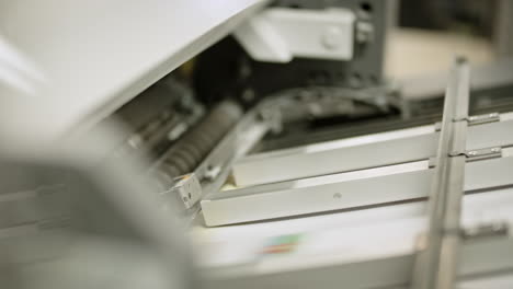 close up of a printing machine, paper traveling on the line in left direction