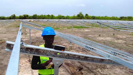 African-engineer-in-blue-helmet-taking-solar-panel-array-beam-structure-tilt-angle-measurements-close-up-shot