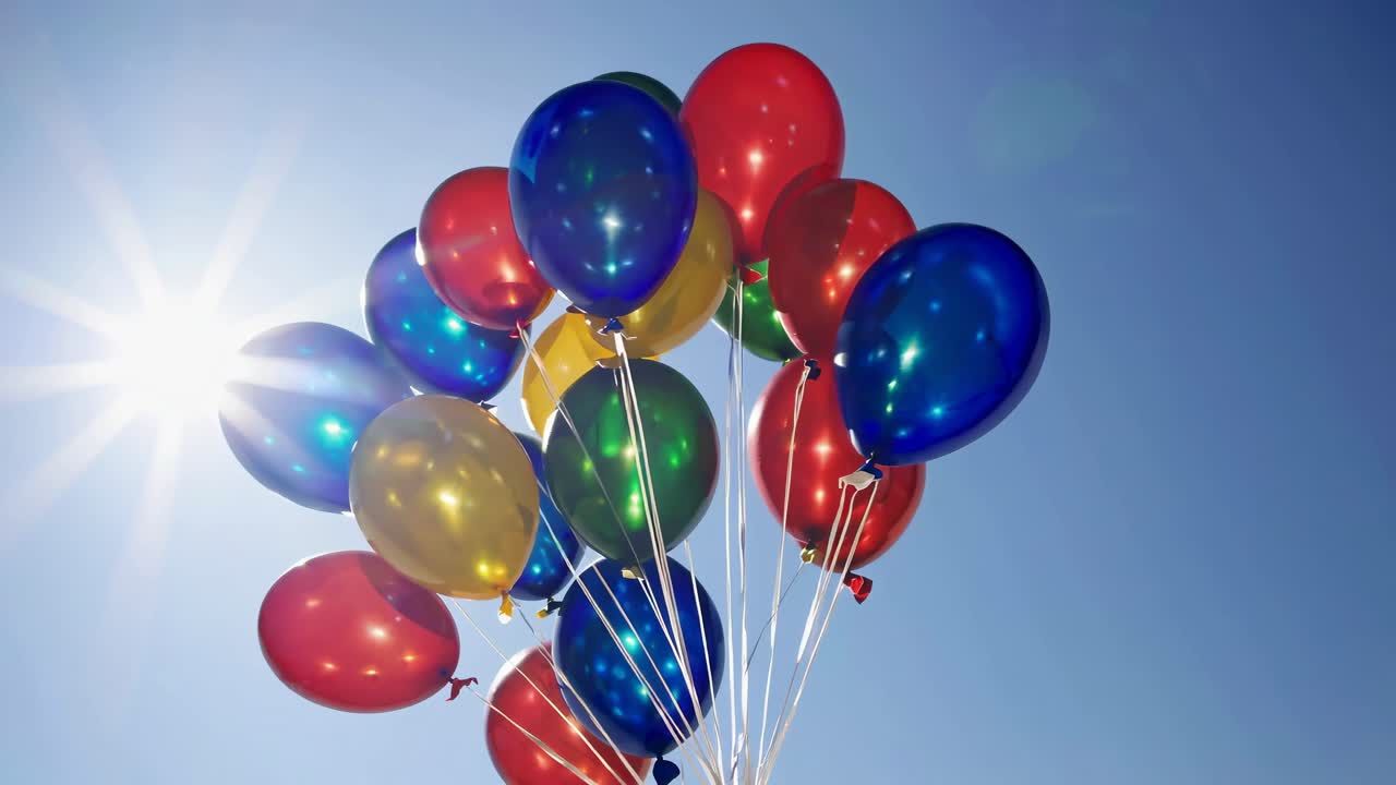 Palloncini vivaci su un cielo azzurro terso con luce solare, ripresi da un angolo inferiore